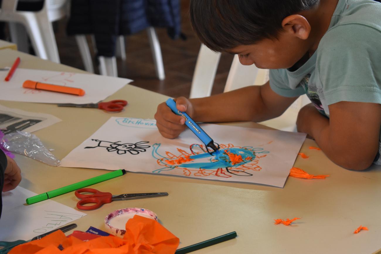 Niño participante del Club de Niños de Salto pinta sobre una hoja de papel.